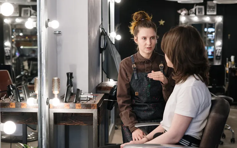 Hair stylist consulting with a client in a warm salon setting